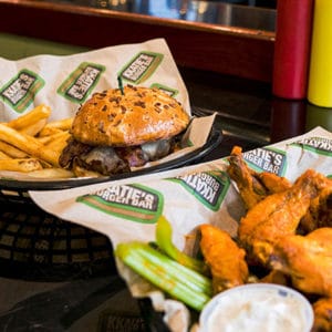 Basket of wings and basket with a juicy burger on onion roll with a side of french fries at KKaties Burger Bar