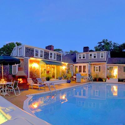 Lamb and Lion pool area at twilight, lounge chairs, looking at a classic cape cottage facade