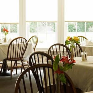 Interior of Old Yarmouth Inn Dining room, colonial chairs, fresh flowers, large windows & sunlight