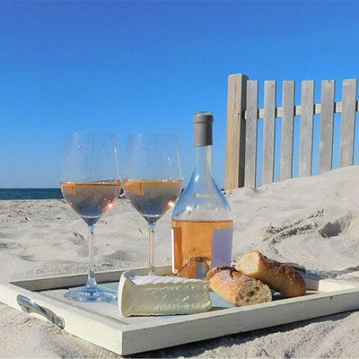 wine, cheese and bread on a tray at the beach