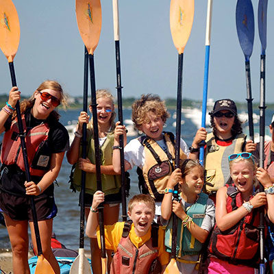 Kids holding paddles at strong wings adventure school